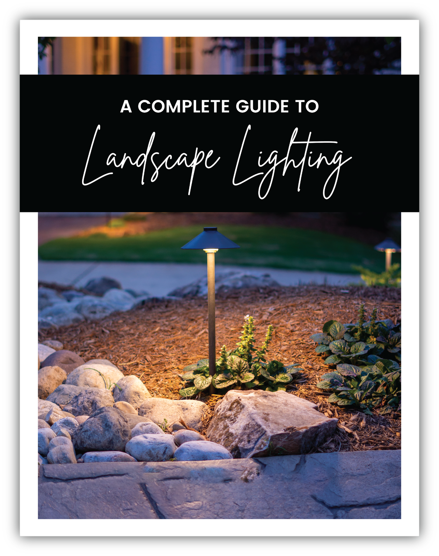 Cover of the Complete Guide to Landscape Lighting. White title on black background with an image of a path light surrounded by plants, mulch, and decorative rocks.