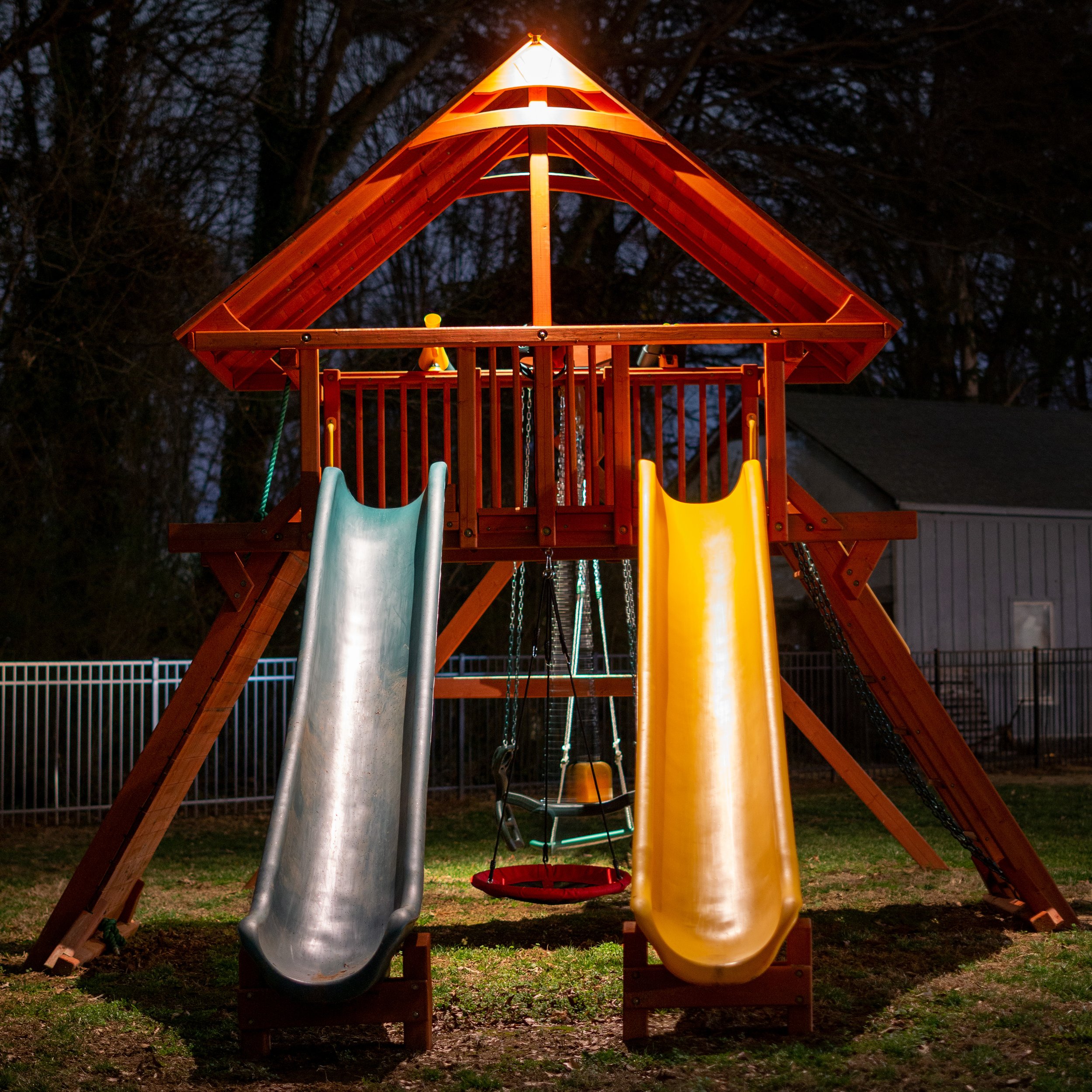 Playset with slides is illuminated with landscape lighting. A series of downlights are mounted in the peaks of the playset.